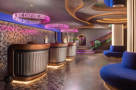 A modern lobby with a check-in counter, seating area, and a staircase.