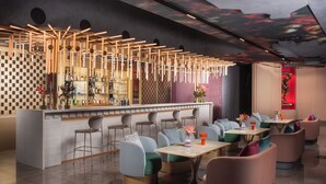 Un espace bar moderne avec un mur à carreaux, des lambris en bois et divers types de sièges, notamment des tabourets de bar et des fauteuils rembourrés.