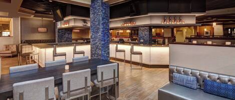 A modern hotel lobby with a dining area, a bar, and a seating area.