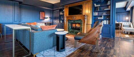 A modern living room with a fireplace, blue walls, and a wooden floor.