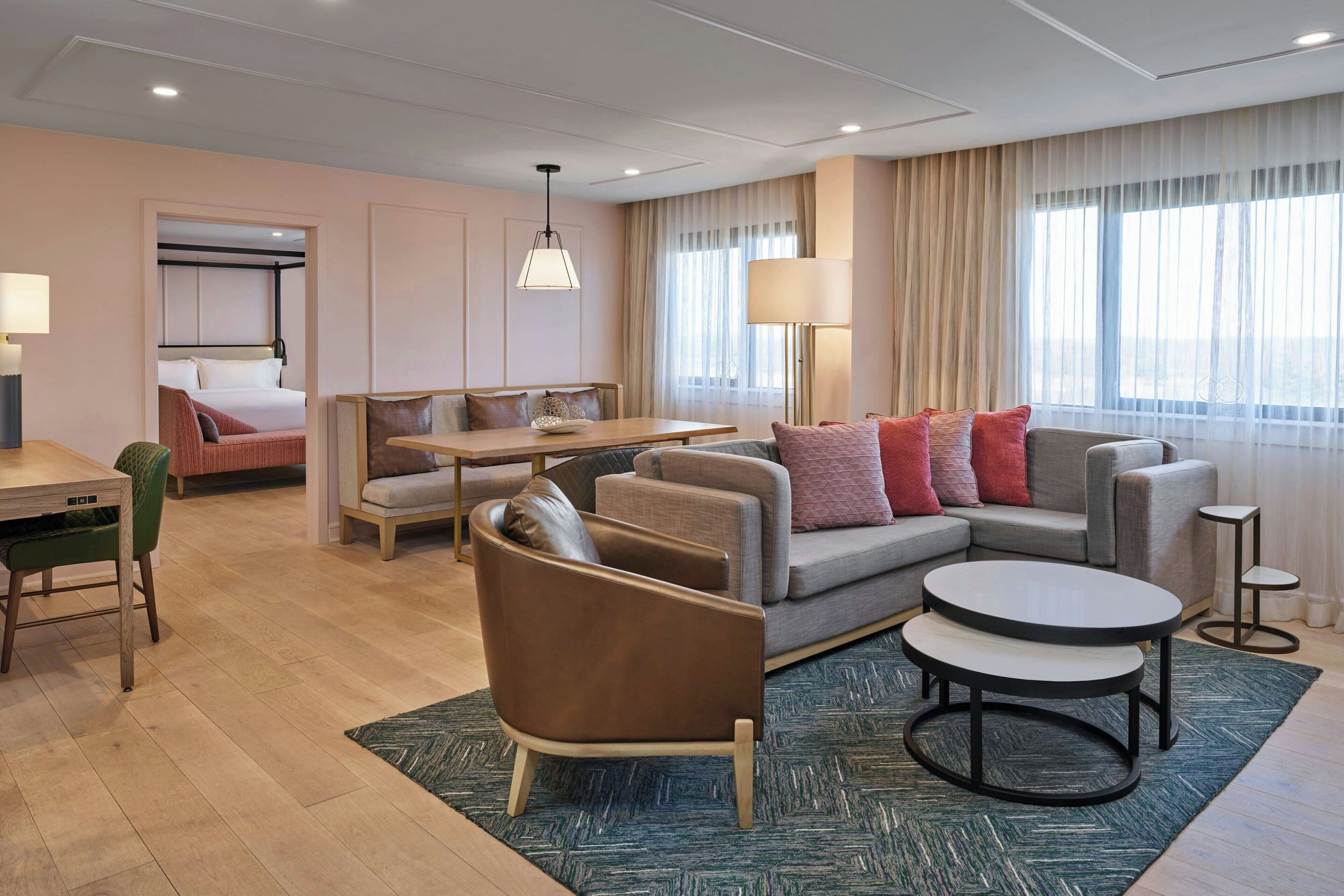 Una habitación de hotel moderna con sala de estar, una mesa de comedor, sofá y cama.