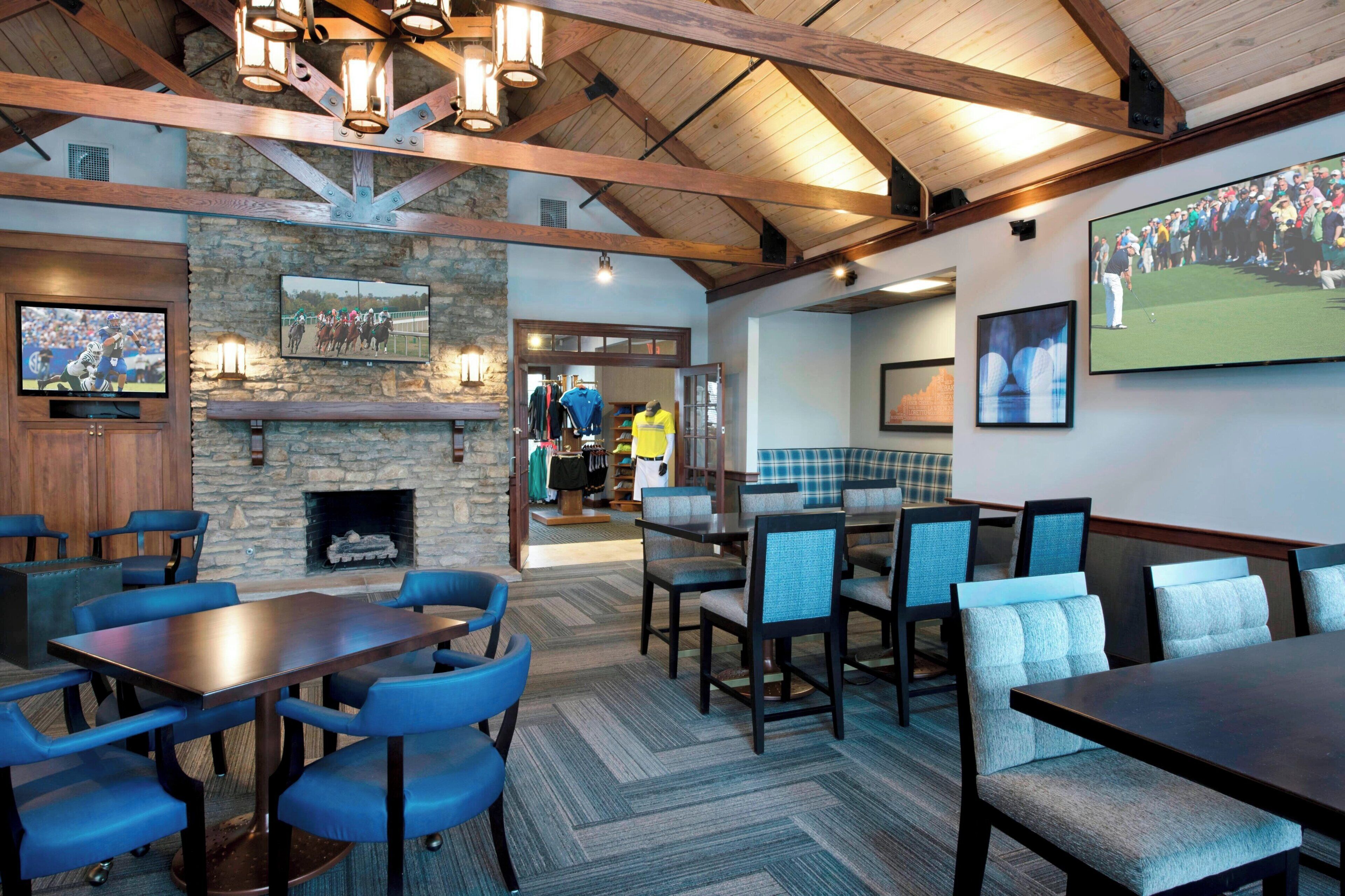 A restaurant with wooden beams, stone walls, and a fireplace. There are tables and chairs for dining.