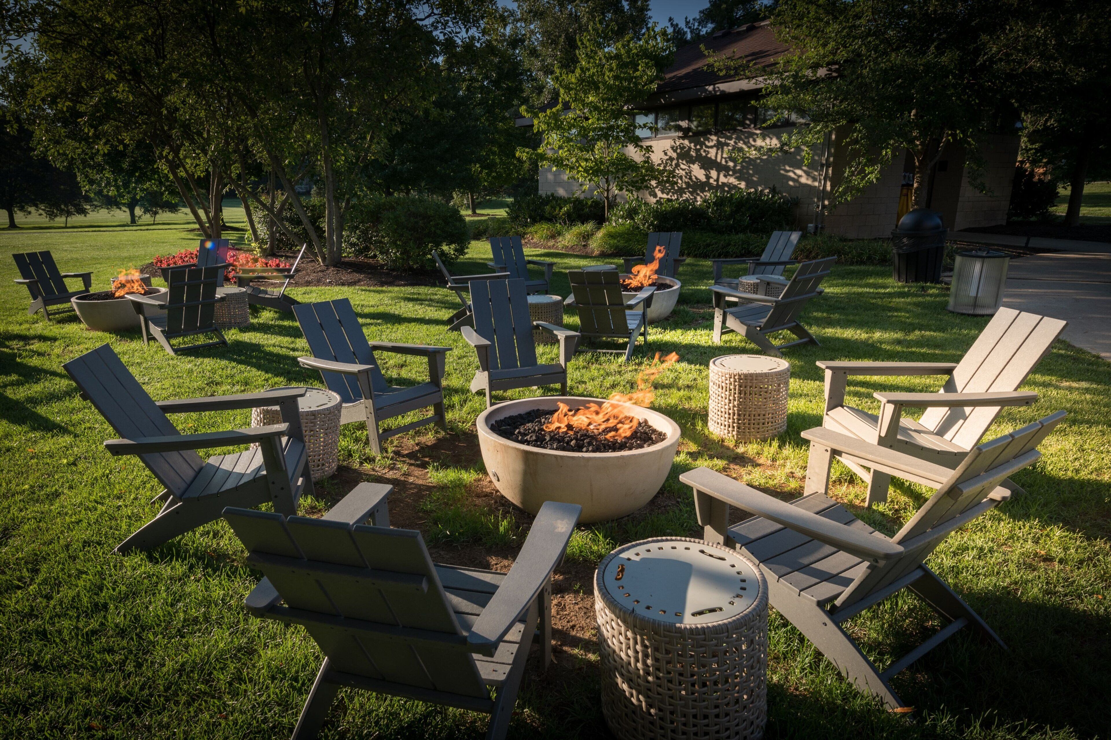 An outdoor seating area with Adirondack chairs and a central fire pit.