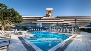 A swimming pool with lounge chairs and umbrellas, a clear sky, and a building with a modern design in the background. - Marriott Lexington Griffin Gate Golf Resort & Spa (Lexington)