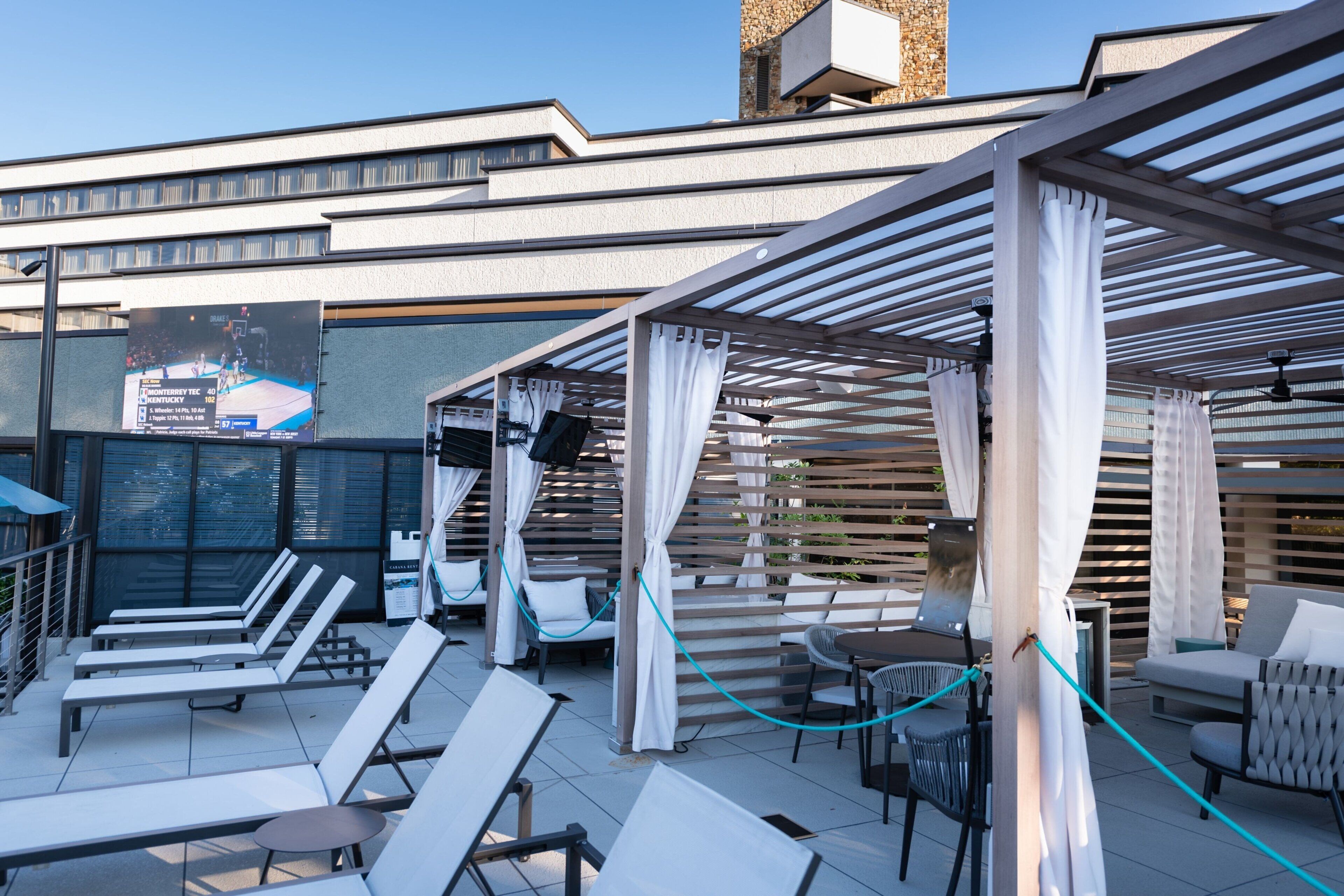 Zona de lounge en la azotea con sillones de sol, un espacio de estar techado y vistas a la ciudad.