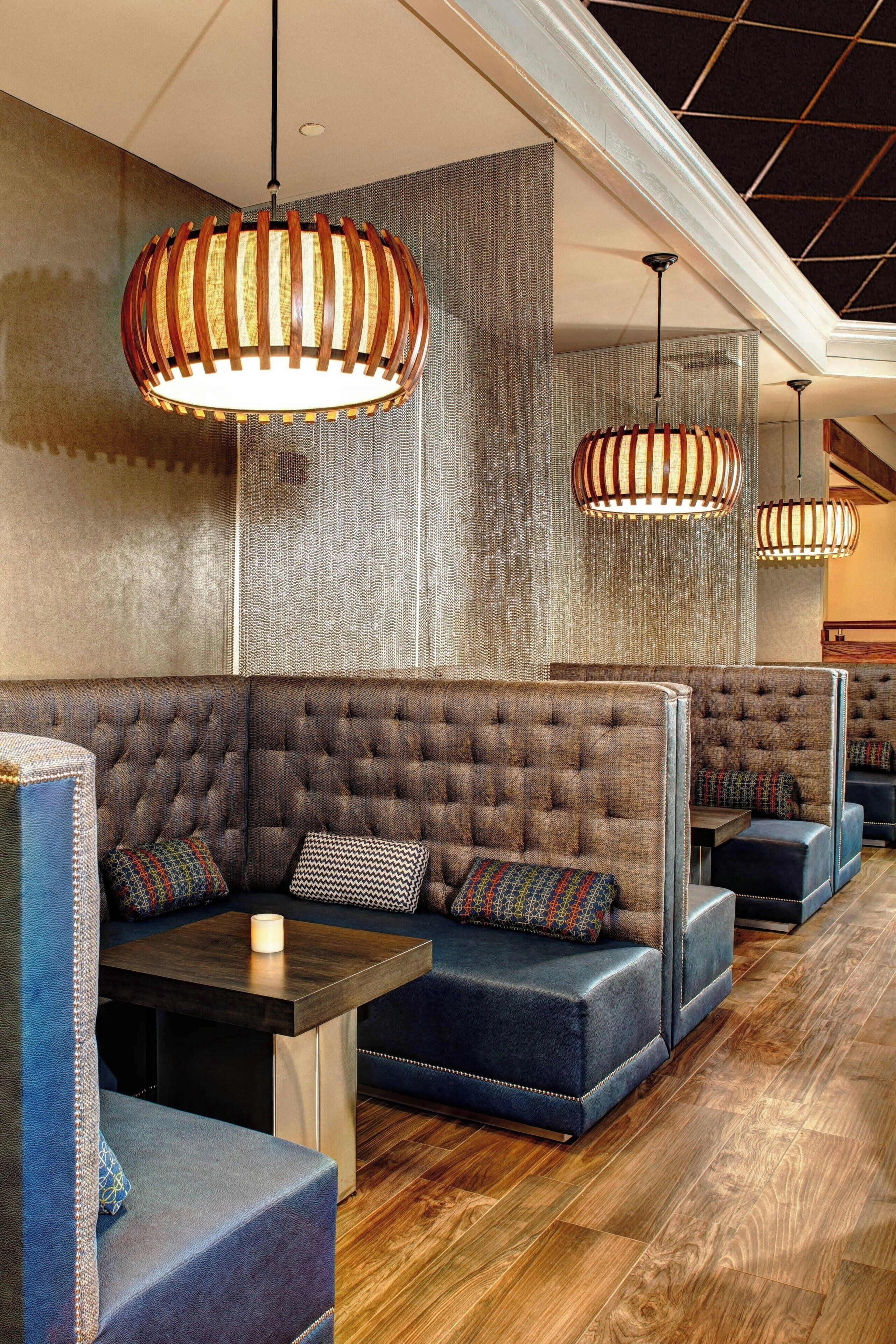 A modern restaurant with booth seating, wooden flooring, and pendant lighting.