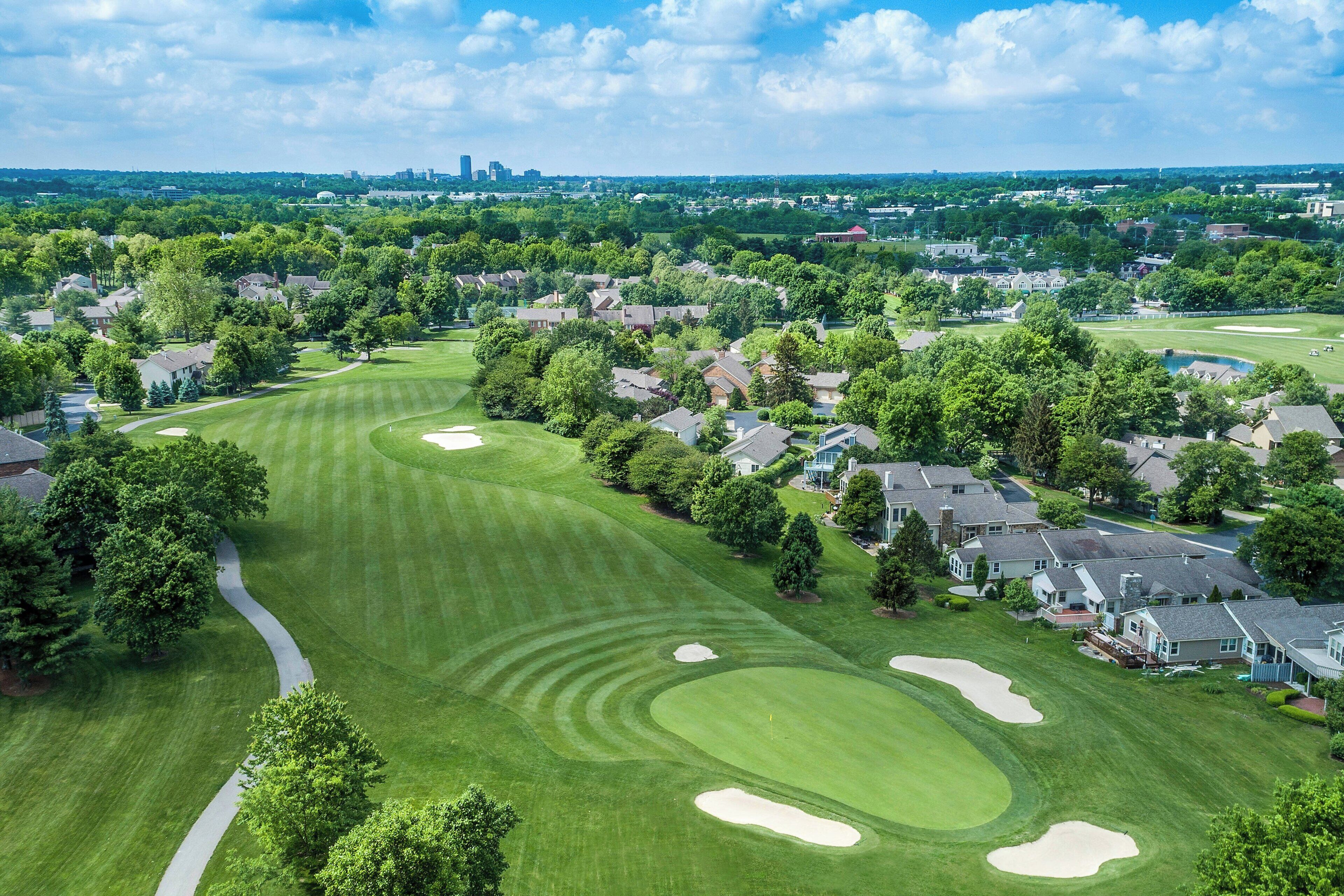 A golf course with a well-maintained fairway, sand bunkers, and a clear sky.