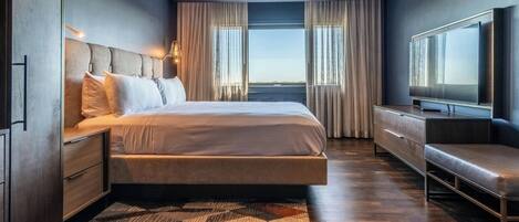 Una camera d'albergo moderna con un letto grande, una televisione e vista sulla città.