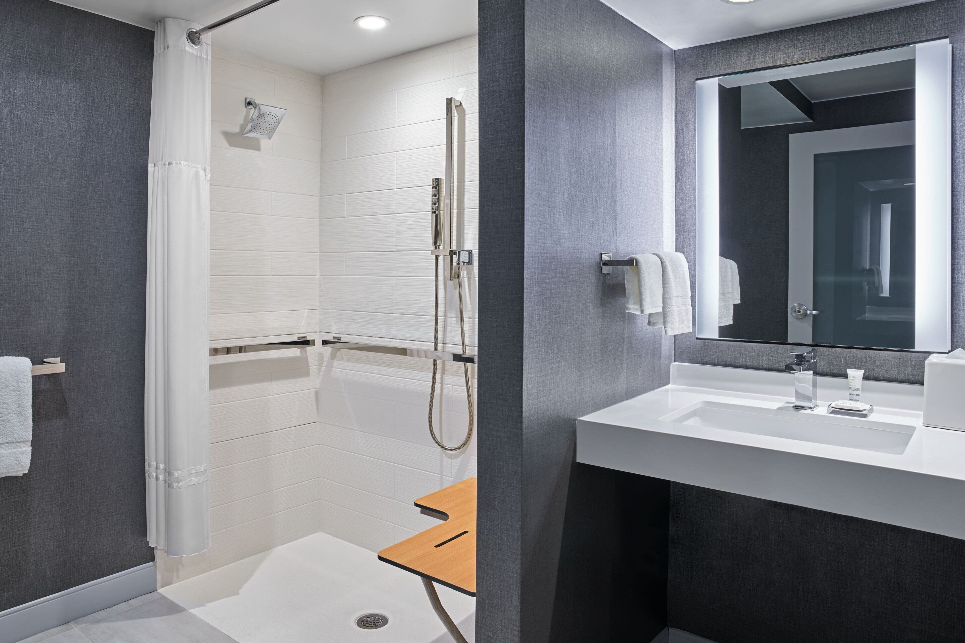A modern bathroom with a walk-in shower, a vanity with a mirror, and a towel rack.