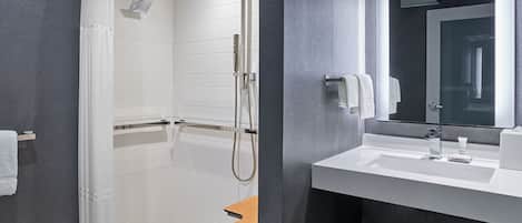 A modern bathroom with a walk-in shower, a vanity with a mirror, and a towel rack.