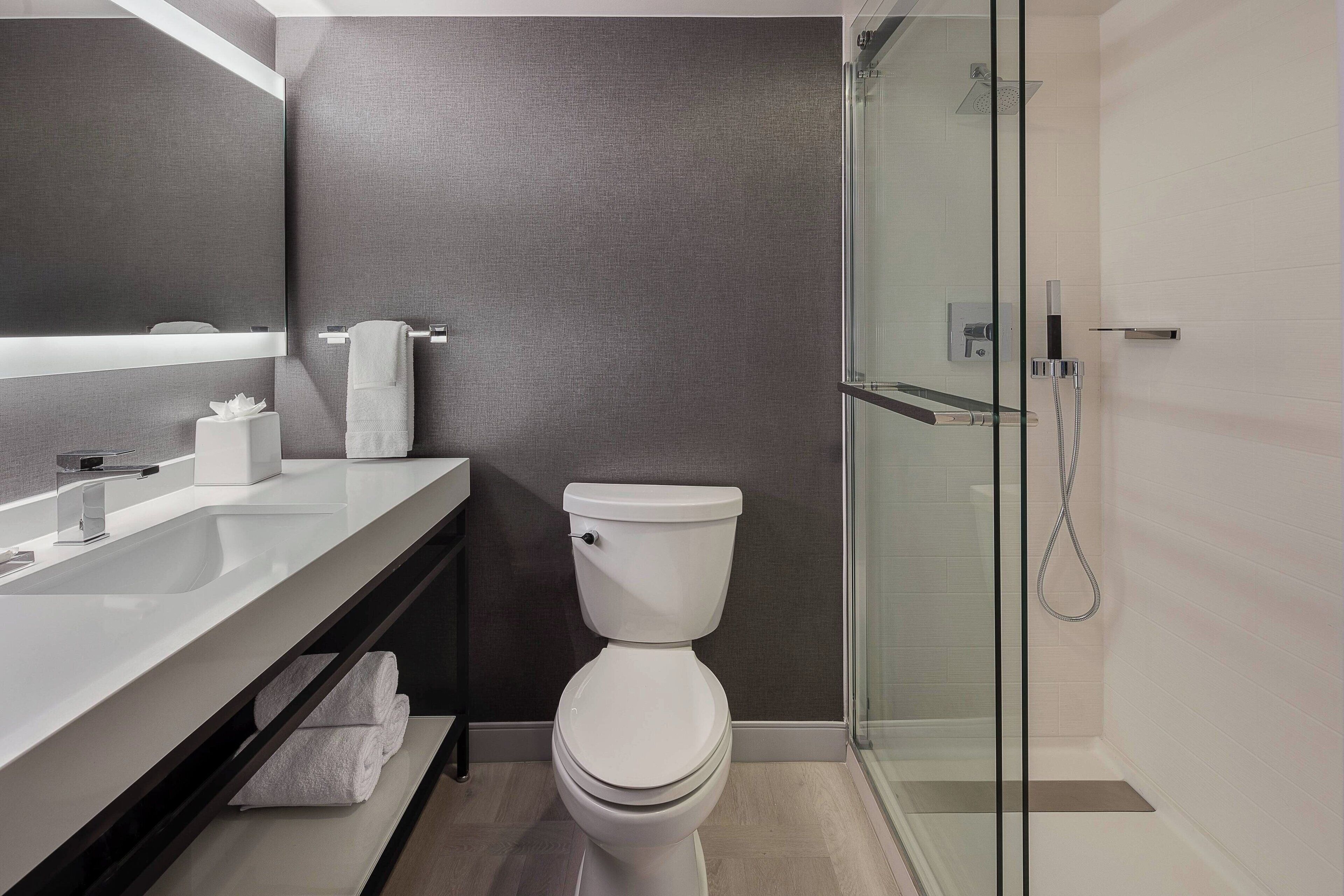 Un baño moderno con cabina de ducha de vidrio, inodoro blanco y tocador doble.