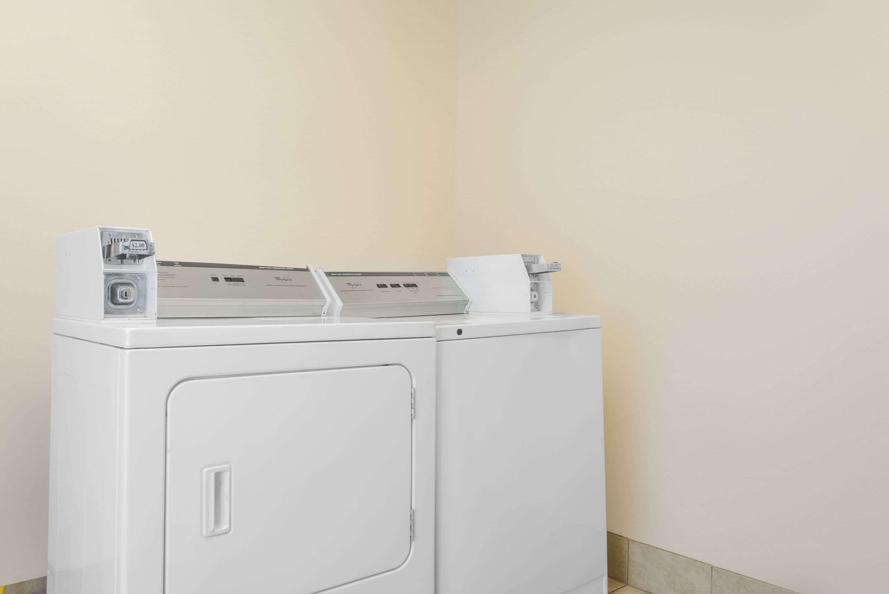 A front-loading white washer and dryer unit with a control panel and a paper towel dispenser on top.