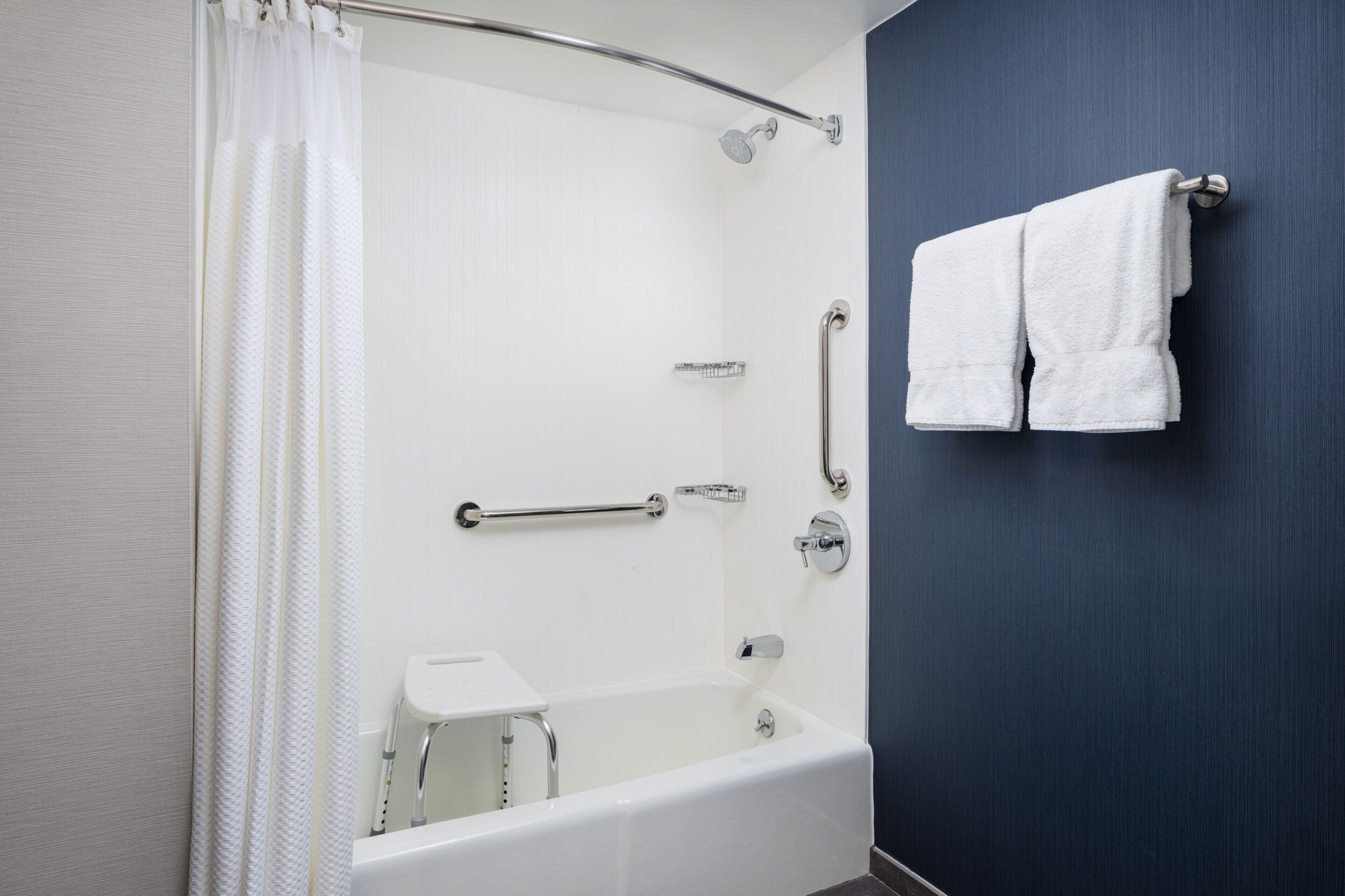 Un baño moderno con bañera, ducha y barras de apoyo.