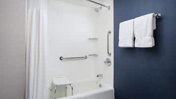 Un baño moderno con bañera, ducha y barras de apoyo.