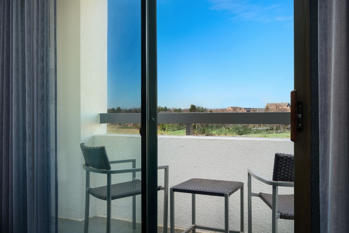 A balcony with a view of a distant landscape, a chair, and a small table.