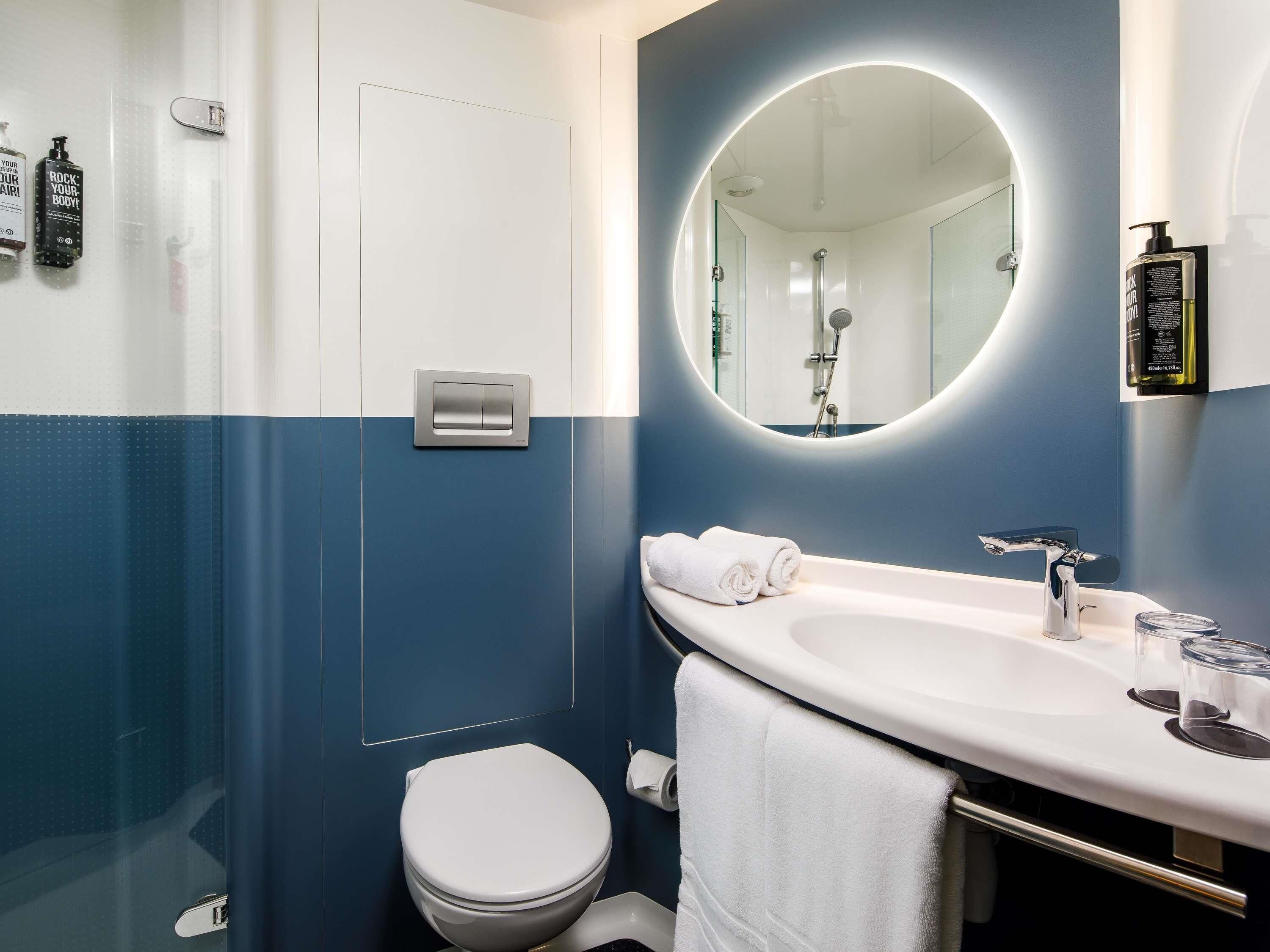 A modern bathroom with a white sink, a mirror, and a shower.