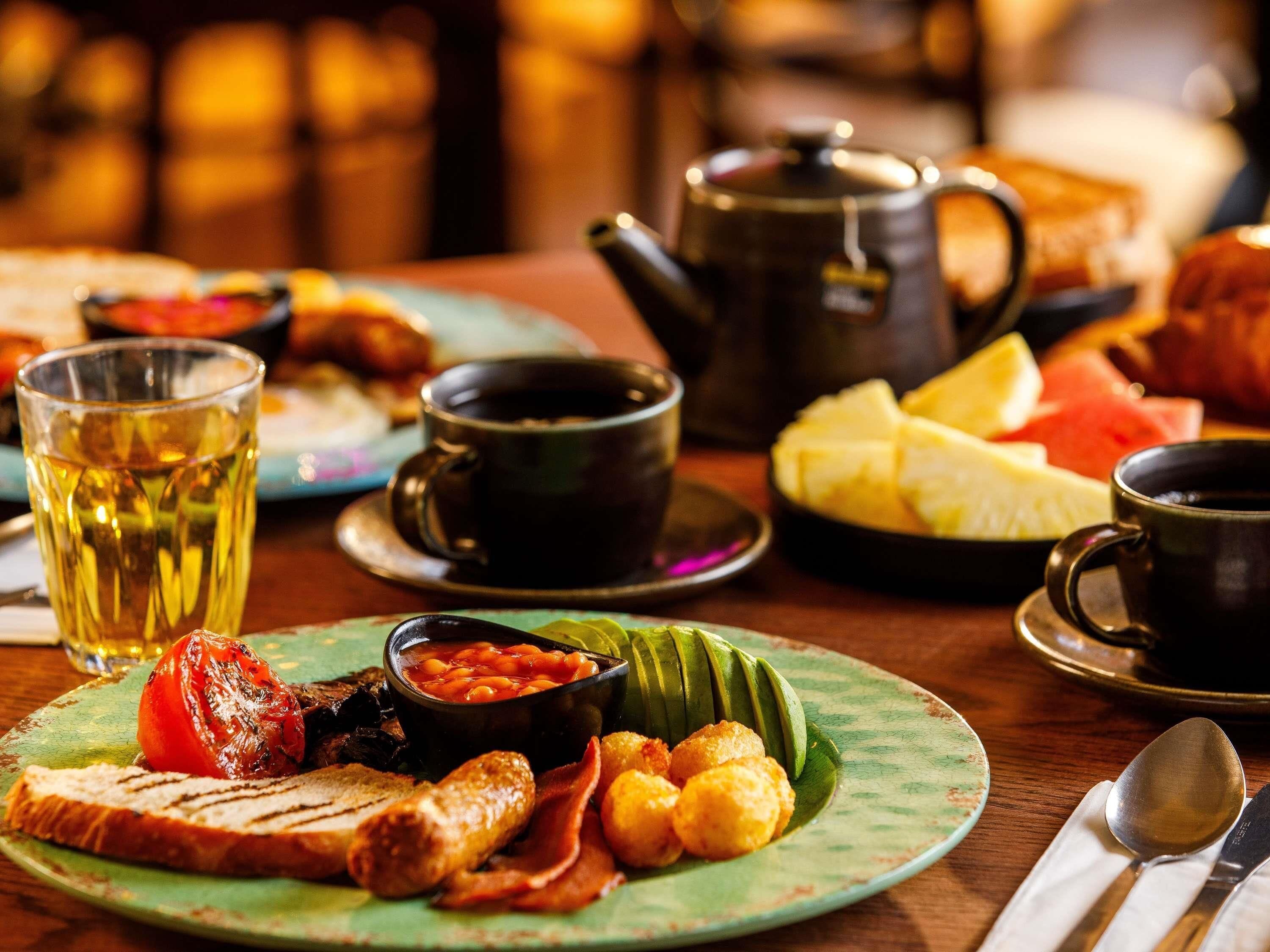 A breakfast setting with a plate of food, a teapot, and cups.