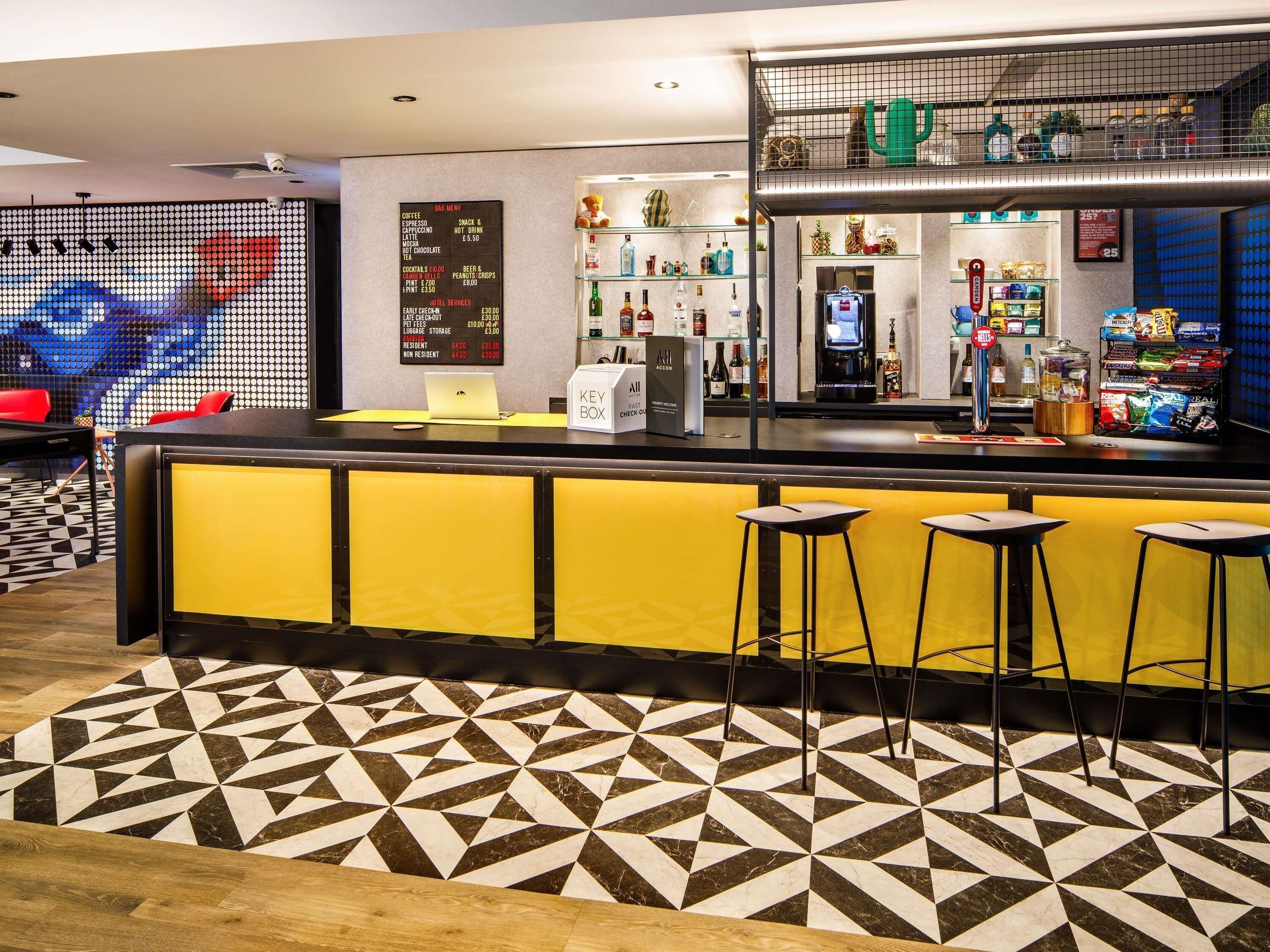 A bar area with stools, a laptop, and a key box on the counter.