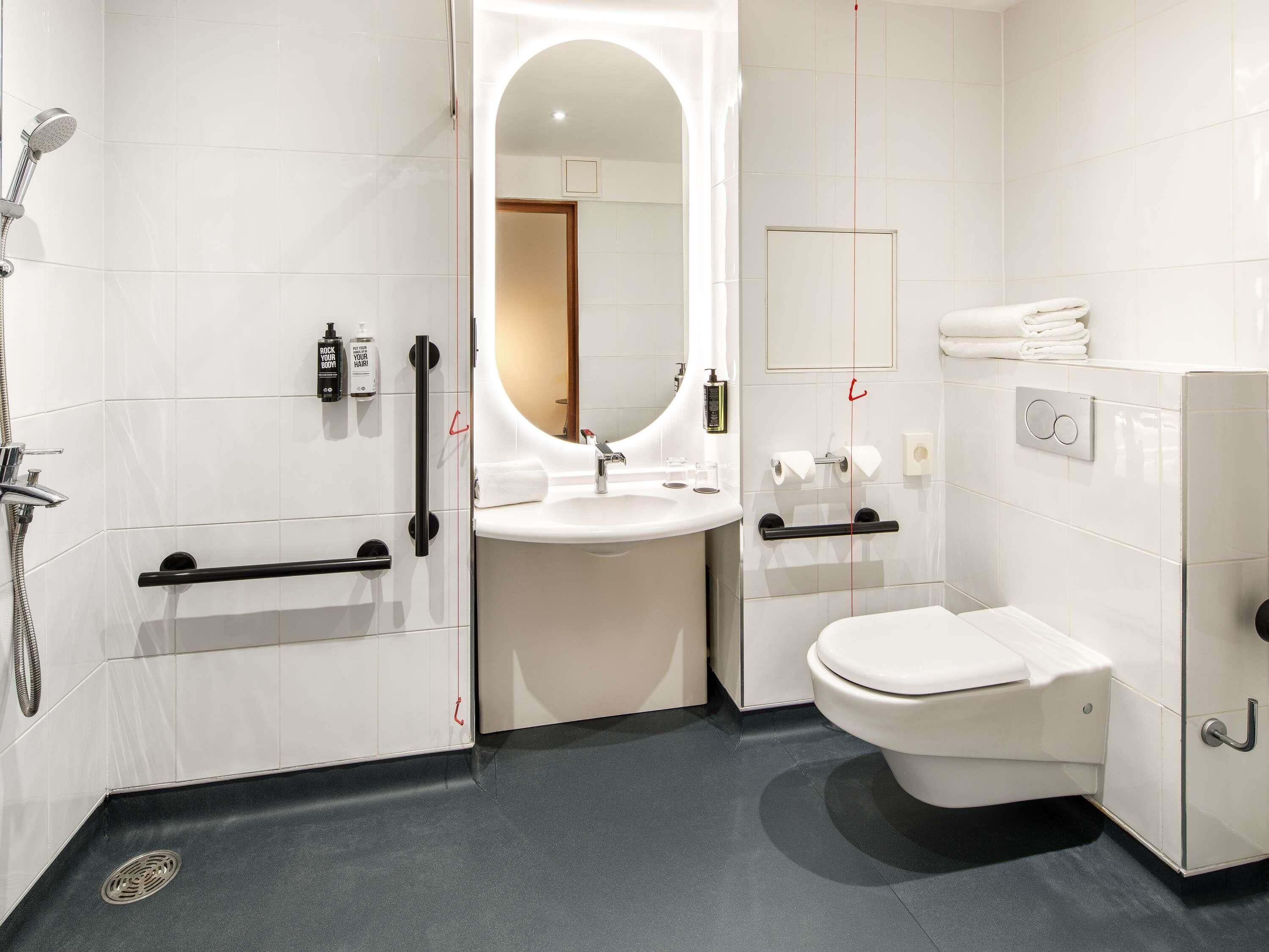 A modern bathroom with a shower, sink, and toilet.