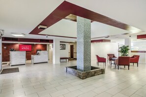A hotel lobby with a reception desk, free Wi-Fi sign, seating area, and a decorative column. - Red Roof Inn PLUS+ Wichita East (Wichita)