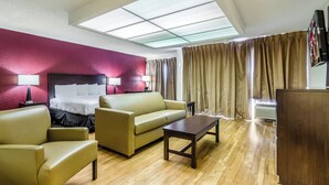 A hotel room with a bed, a sofa, a coffee table, and a TV.