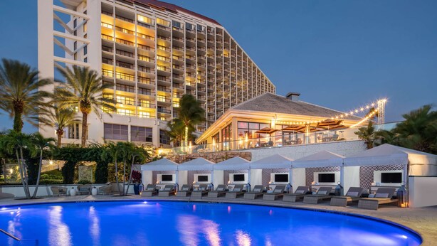 A hotel with a large pool, multiple balconies, and outdoor seating areas. - Naples Grande Beach Resort (Naples)