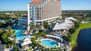 A large hotel with multiple swimming pools, a central courtyard, and a view of the surrounding landscape. - Naples Grande Beach Resort (Naples)