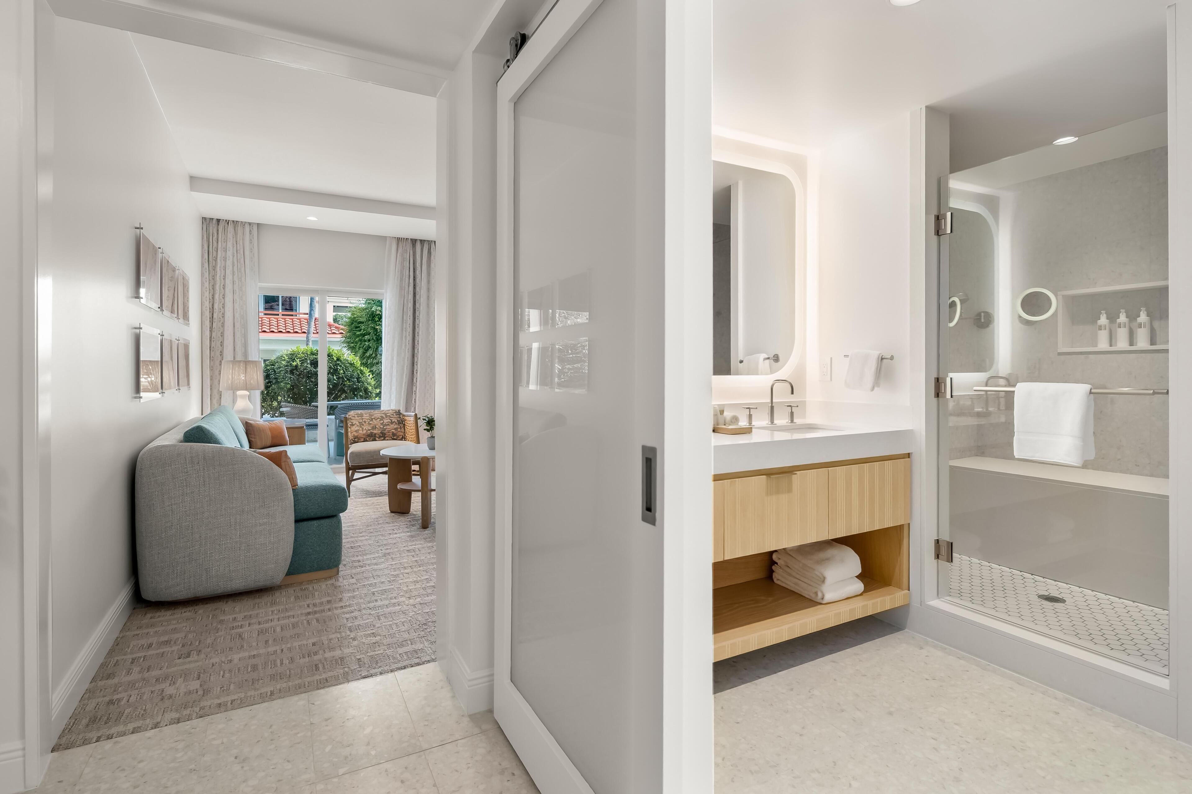 A modern bathroom with a glass-enclosed shower, a vanity with a mirror, and a towel rack.