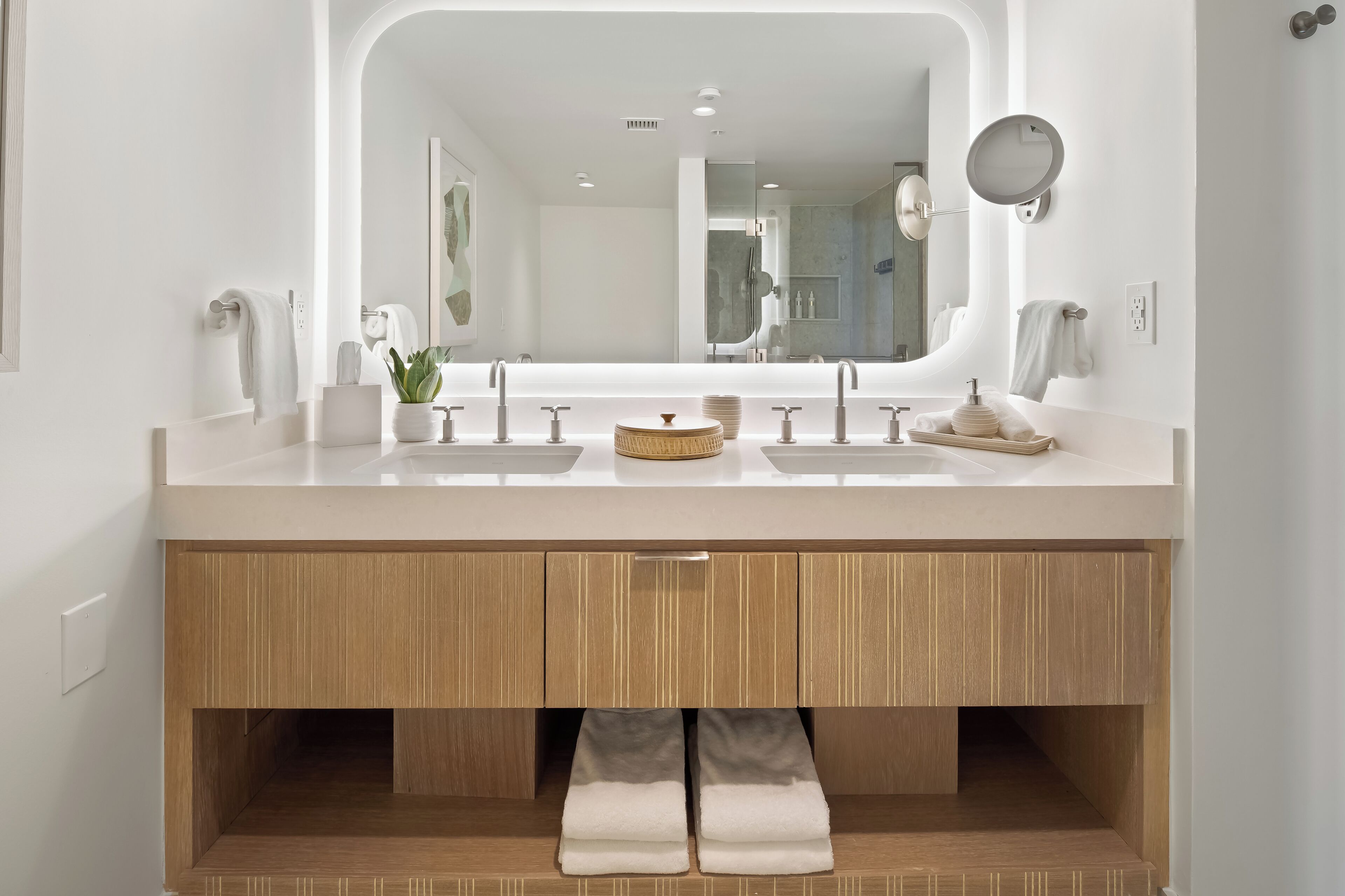 Un baño moderno con tocador doble, muebles de madera y un espejo grande.