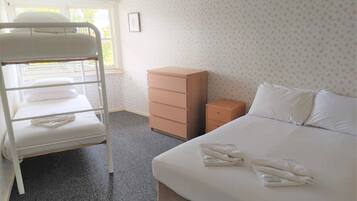 A hotel room with a bunk bed, a single bed, a dresser, and a small cabinet.