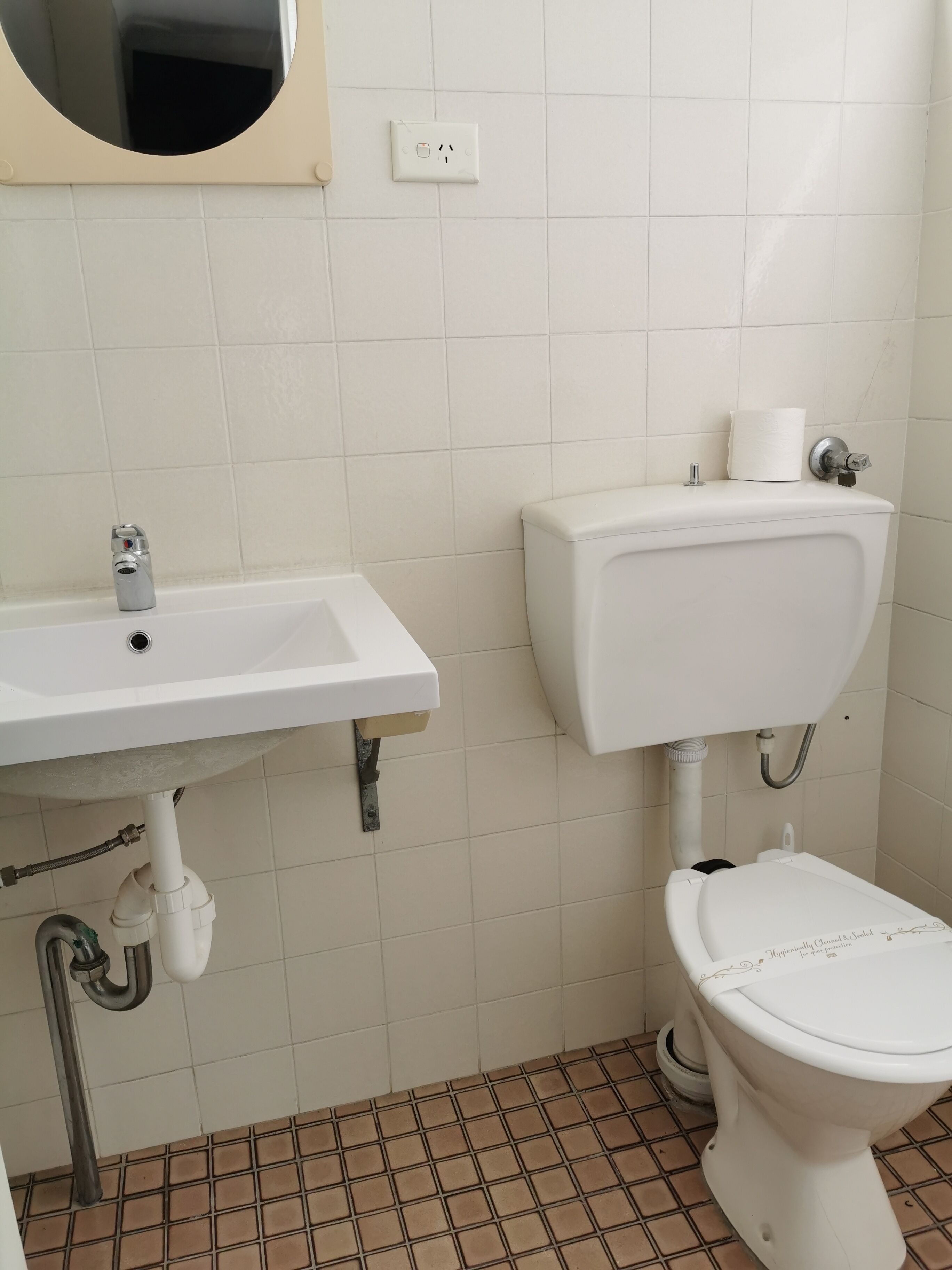 A bathroom with a white sink, toilet, and tiled floor.