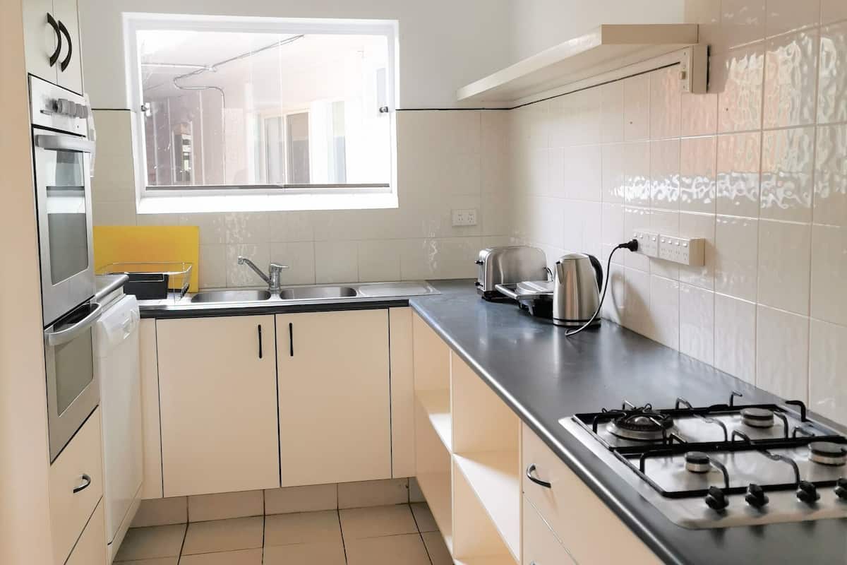 A modern kitchen with white cabinets, a black countertop, a gas stove, and a window providing natural light.