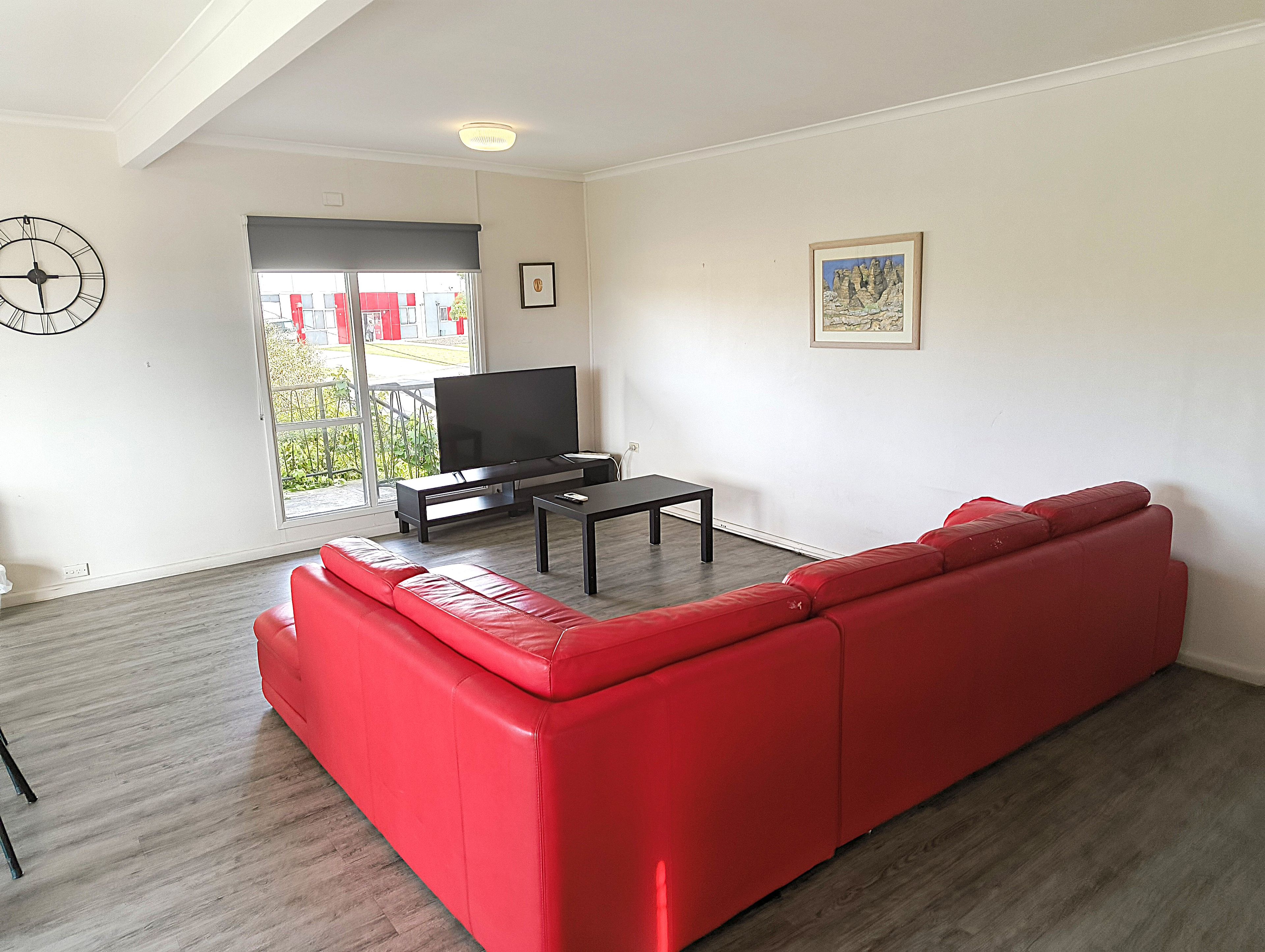 A living room with a red sofa, a flat-screen TV, and a coffee table.