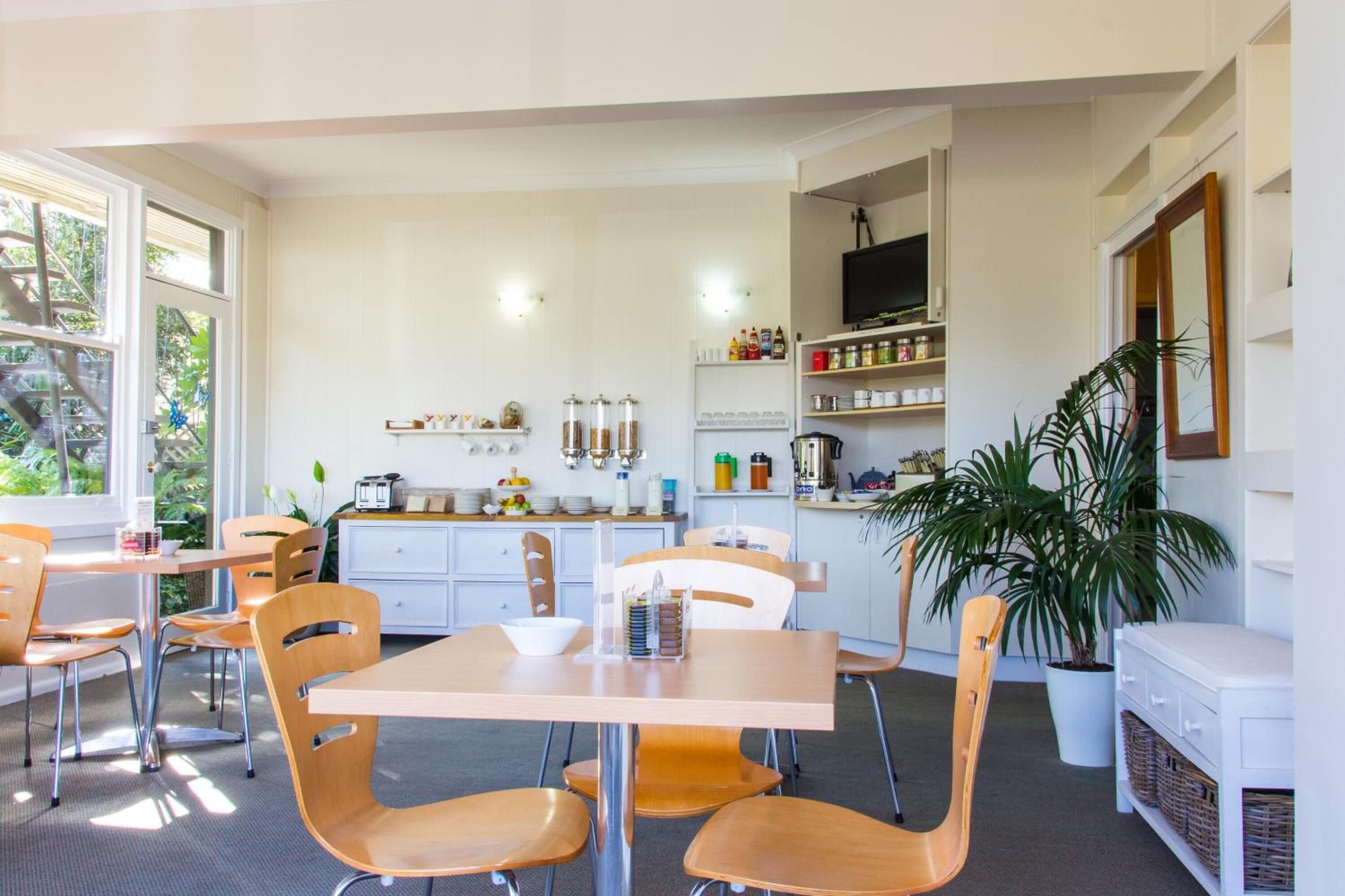 Een moderne keuken met witte kasten, een eethoek met houten stoelen en een grote potplant.