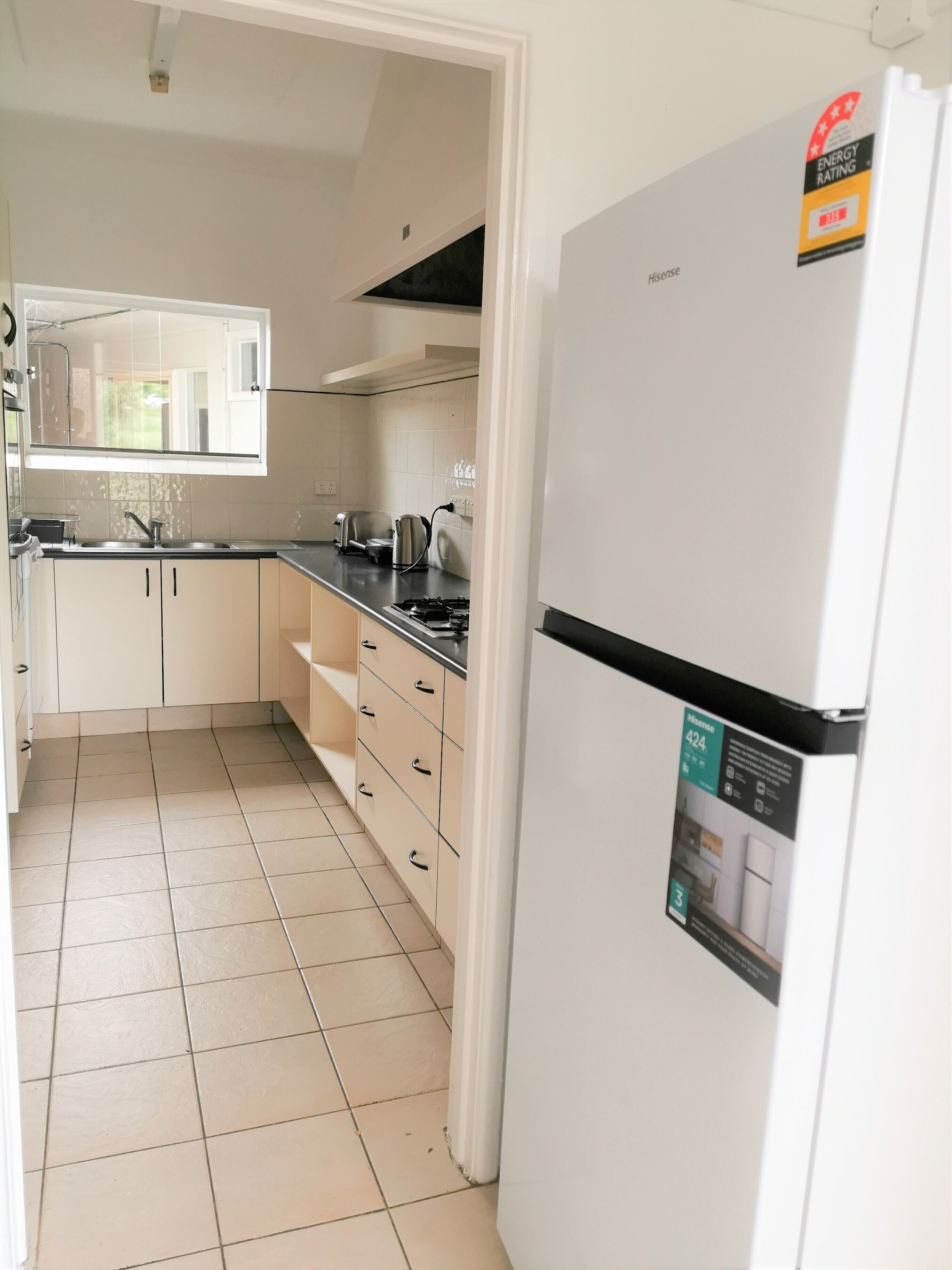 A kitchen with white cabinets, a stainless steel sink, a gas stove, and a refrigerator with an energy rating sticker.