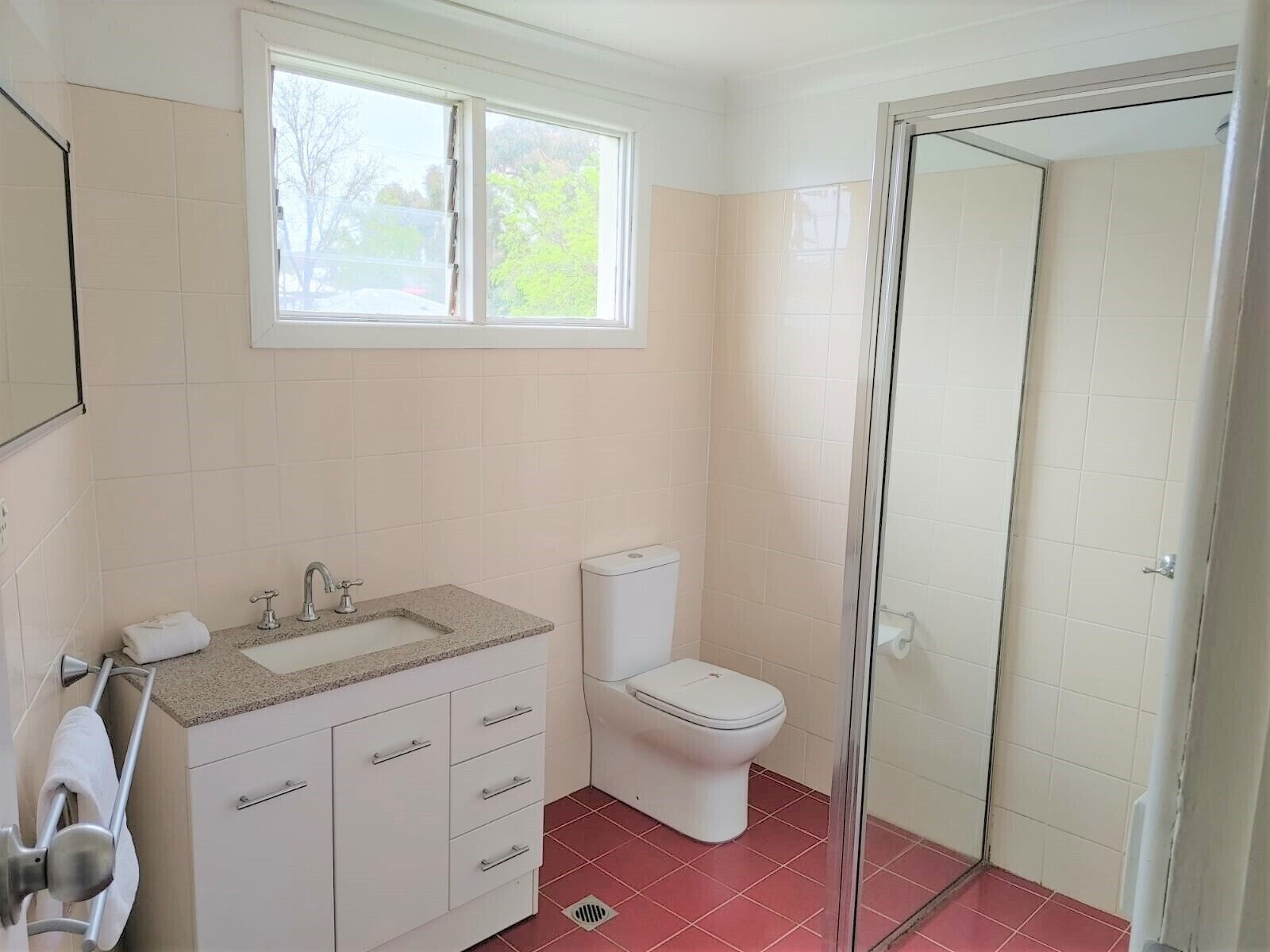 Ein Badezimmer mit Fenster, Waschbecken, Toilette und Dusche.