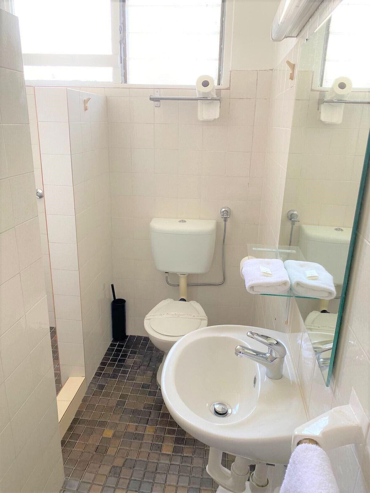 A small bathroom with a toilet, sink, and a glass shower enclosure.