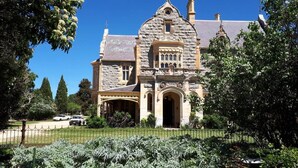 A large, historic building with a prominent entrance, surrounded by lush greenery and a fenced garden. - Bathurst Explorers Motel (Bathurst)