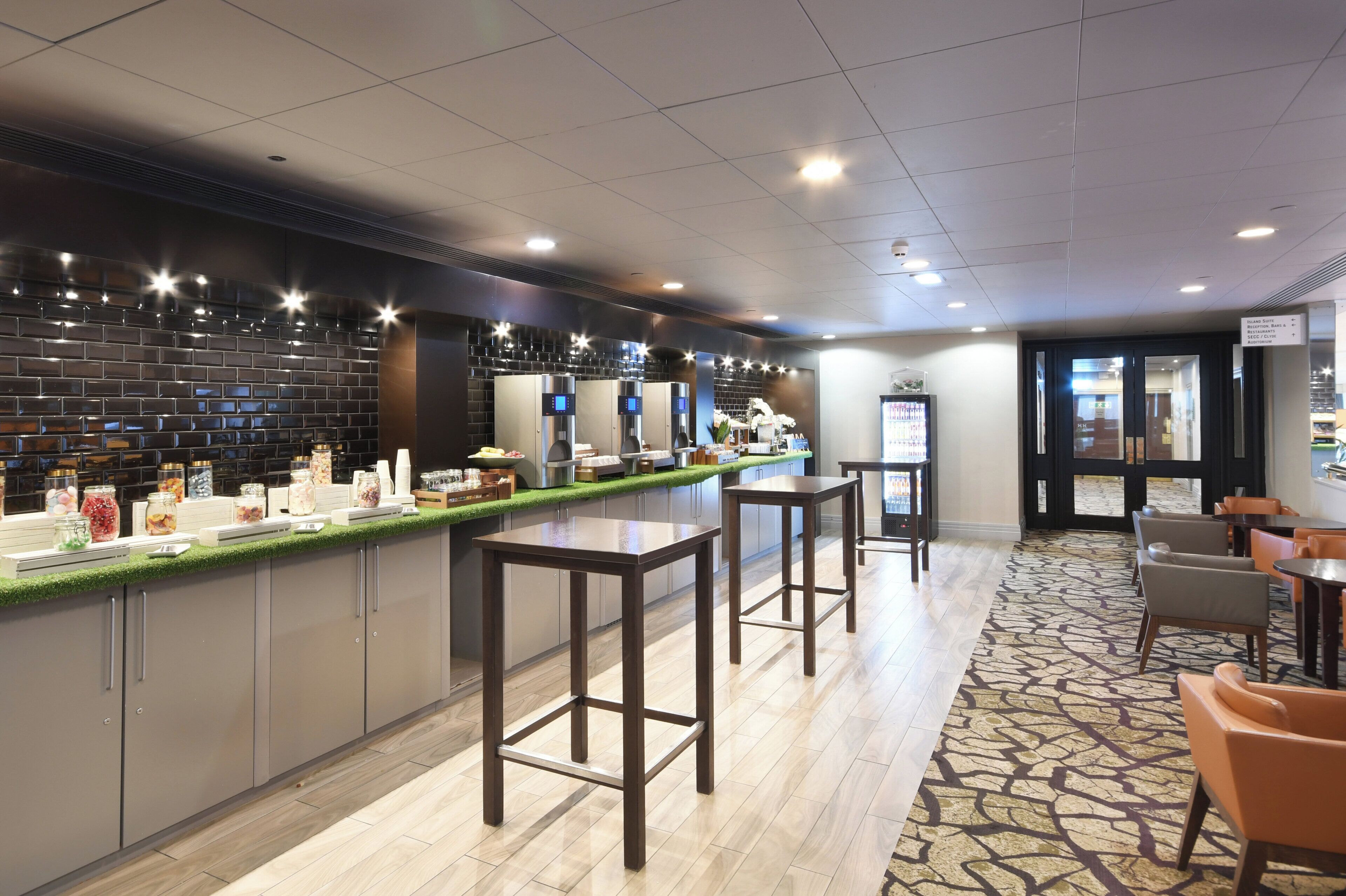 A hotel bar with a counter, stools, and a patterned carpet.