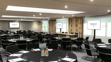 A conference room with multiple tables, chairs, and presentation screens.