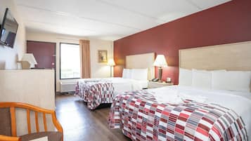 A hotel room with two beds, a desk, a chair, a TV, and a window with curtains.