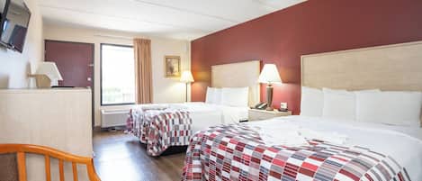 Ein Hotelzimmer mit zwei Betten, einem Schreibtisch, einem Stuhl, einem Fernseher und einem Fenster mit Vorhängen.