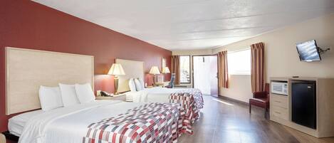 Habitación de hotel con dos camas, televisor, escritorio y ventana con cortinas.