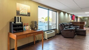 A room with a coffee machine, a seating area, and a view of the outdoors.