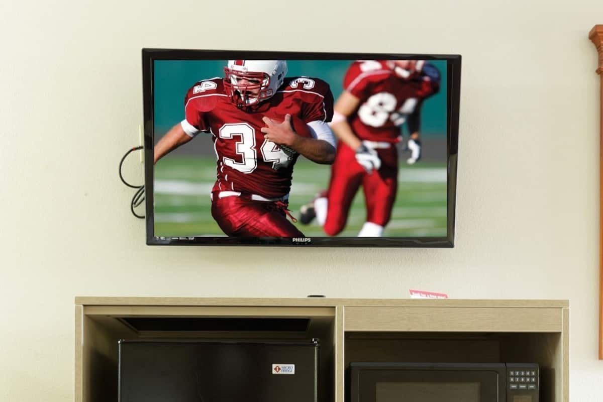 A refrigerator and microwave built into a cabinet with a television above it.