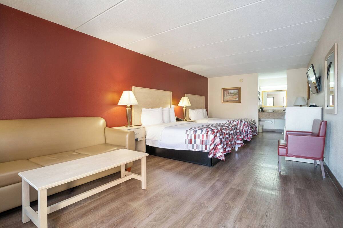 A hotel room with a bed, a sofa, a small table, and a chair.