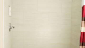 Ducha con piso de azulejos y rociador.