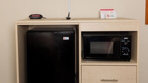 A kitchenette with a black refrigerator, a microwave, and a clock on the countertop.