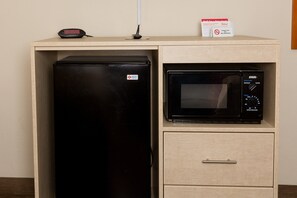 A kitchenette with a black refrigerator, a microwave, and a small shelf with a clock and a "No Smoking" sign. - Red Roof Inn & Suites Pigeon Forge - Parkway (Pigeon Forge)