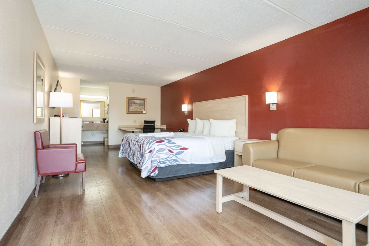 A hotel room with a bed, a sofa, a desk, and a chair.